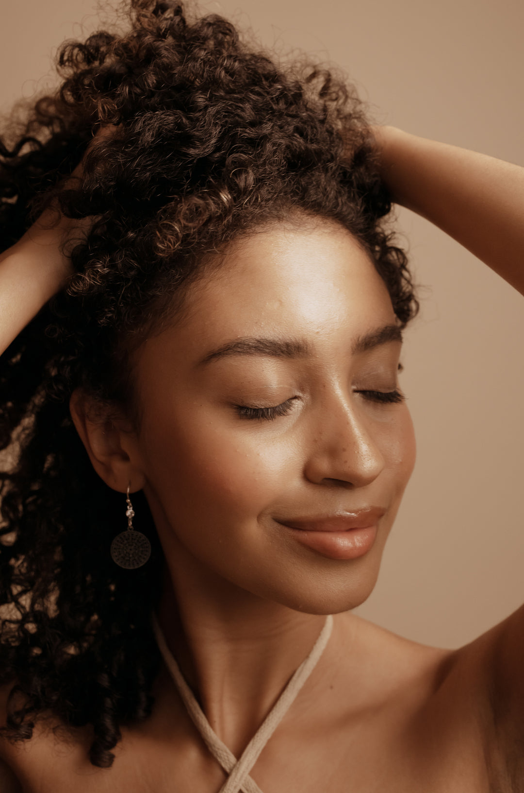 beautiful model applying organic hair oil product on gorgeous black curly hair